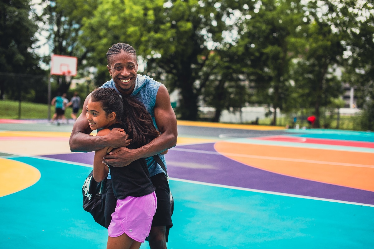 Father and daughter hugging on basketball court